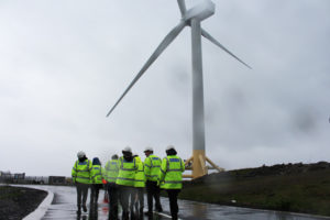 The committee approaches the 7MW wind turbine in the pouring rain