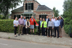 A group of 12 people standing on the pavement outside a home.