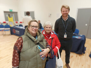 Three people posing and smiling in a large indoor room