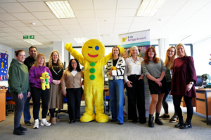 A group of people standing with a gingerbread man mascot
