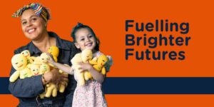 A mother and daughter smiling and holding soft toys. Caption is 'Fuelling Brighter Futures'