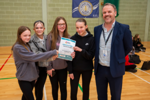 4 children being presented with an award by man in suit