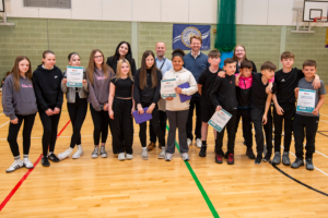 A group of children in school gym with adults in back row
