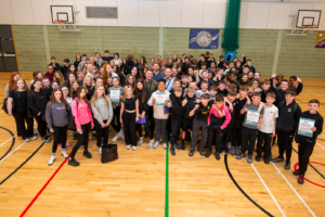 A large group of children in school gym with some adults