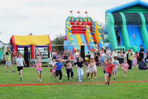 A group of young people in a field with bouncy castles in background